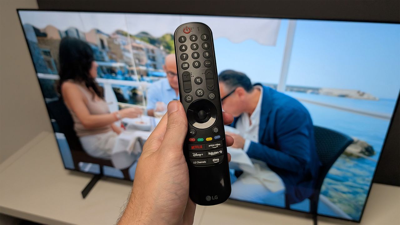 The LG C5 42-inch OLED TV's remote control held in the hand in front of the TV.