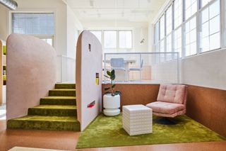 Living area with pink lounge chair, white tiled side table, green carpet and cork flooring and walls