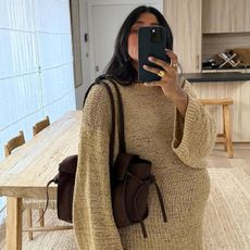 Woman wears beige knit and brown suede bag