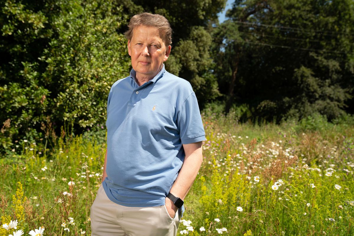 Bill Turnbull in a posed shot in a sunny meadow, relaxed with hands in pockets