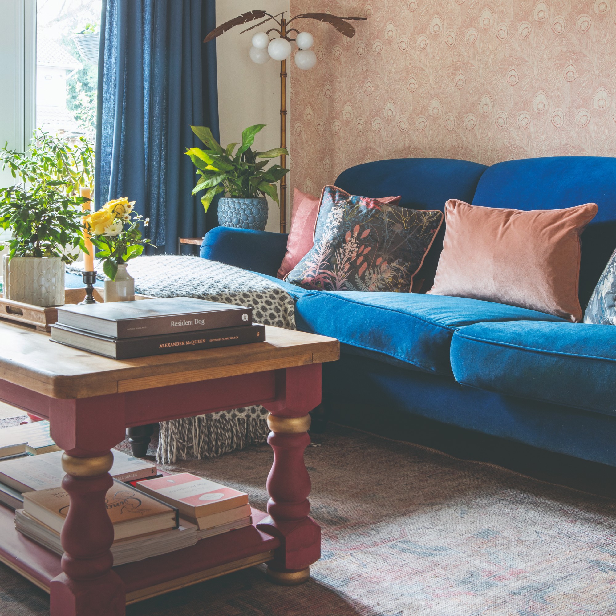 A living room with a blue velvet chaise sofa and a vintage-style rectangular rug