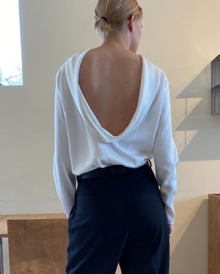 Christie Tyler wearing a white backless Source Unknown top with black pants.