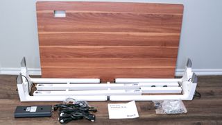 The Branch Four Leg Standing Desk unboxed with all of its parts and pieces up against a wall