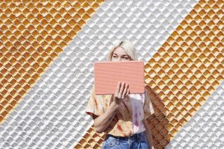 Young woman holds pink Pixelbook Go.