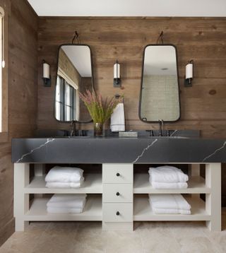 bathroom with natural wood paneled walls matching mirrors and sink unit with open shelves and white towels