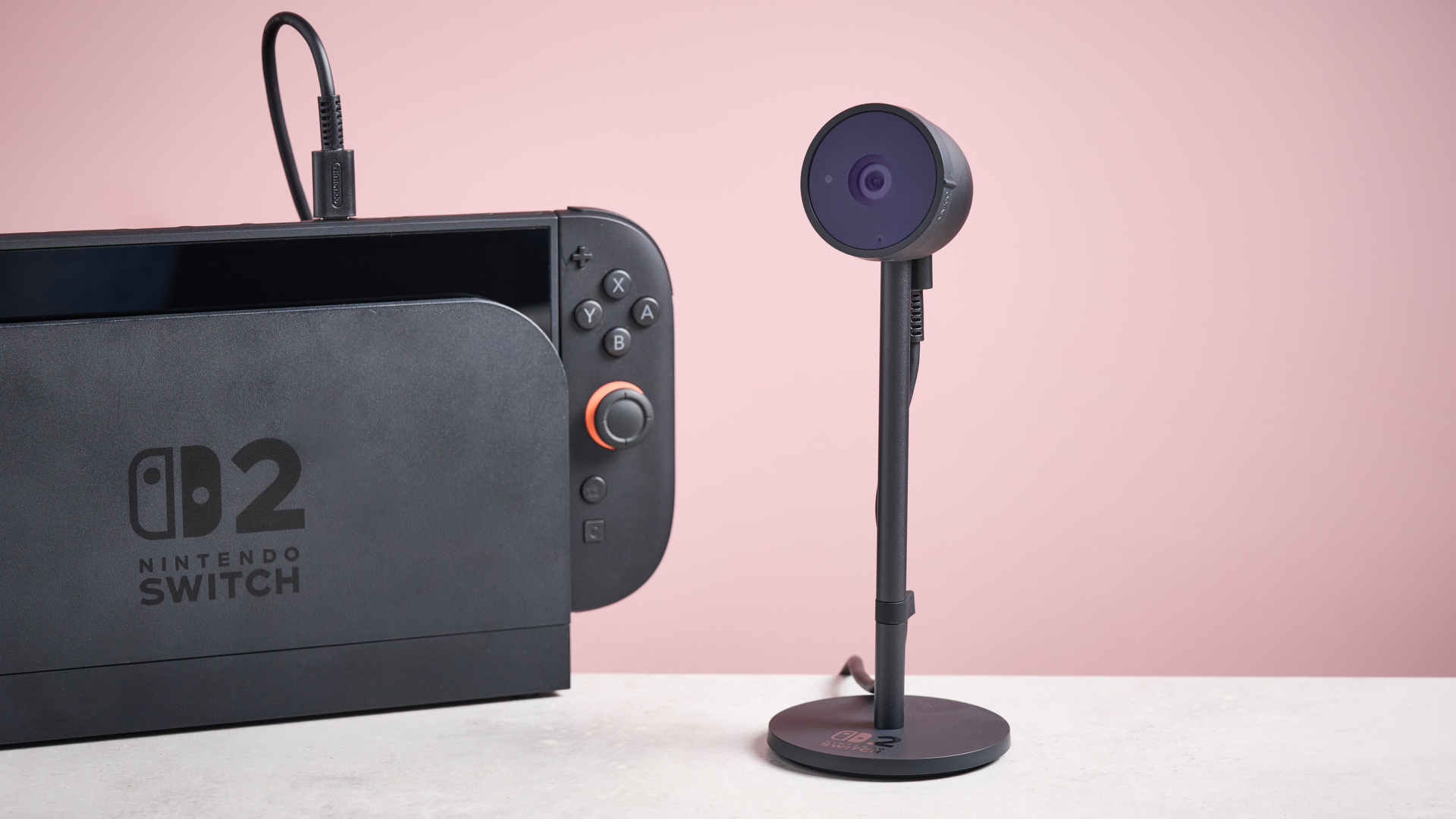 Nintendo Switch 2 camera next to Switch 2 console against pink background