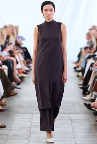 Model walking the Remain fall runway show wearing a purple turtleneck with matching trousers and white pumps.