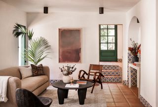 A small living room with a large sofa, two chairs and a small, round coffee table