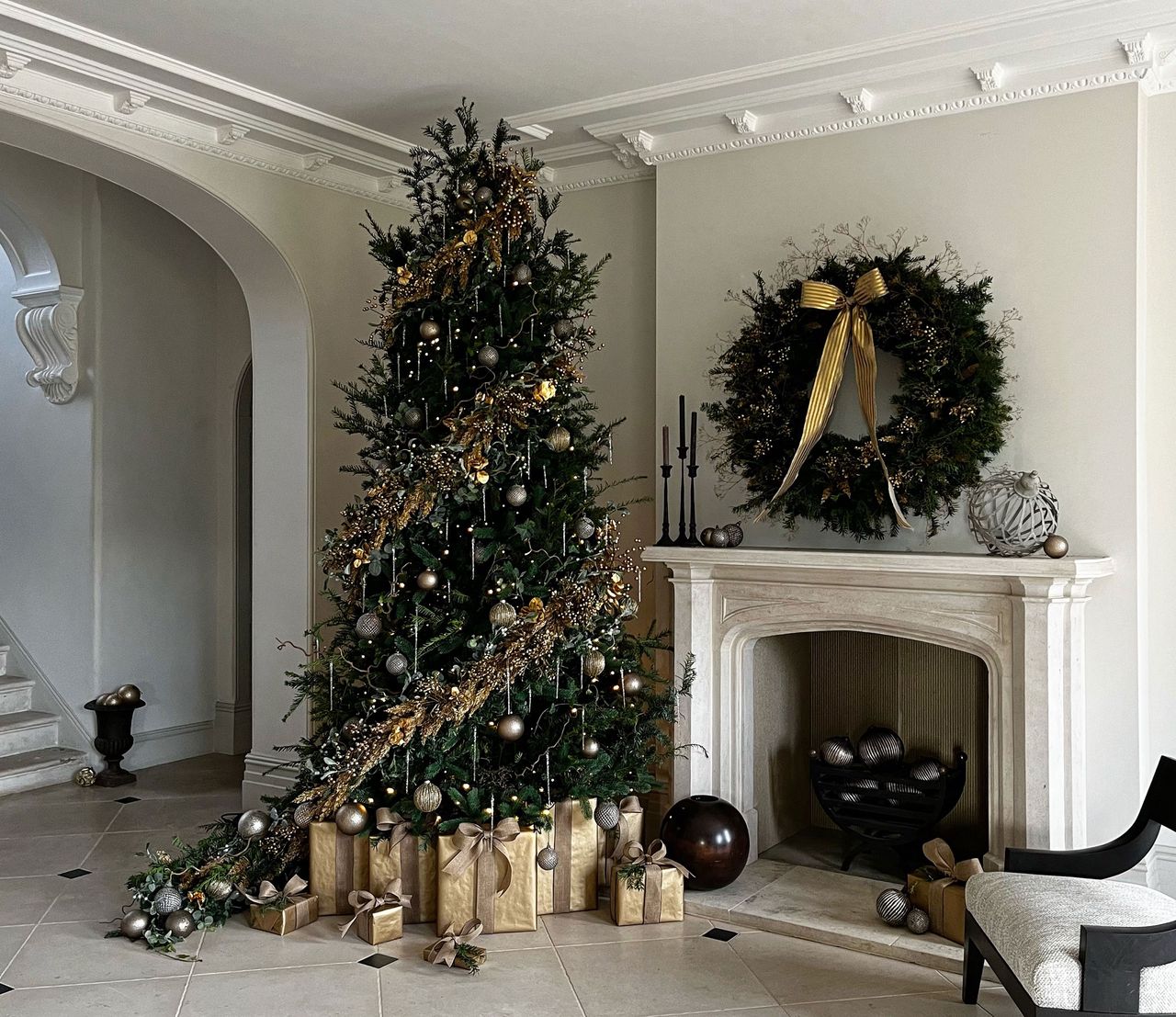 a christmas tree with gold decorations and a wreath over a fireplace