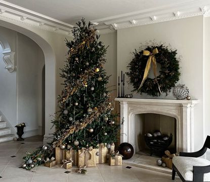 a christmas tree with gold decorations and a wreath over a fireplace