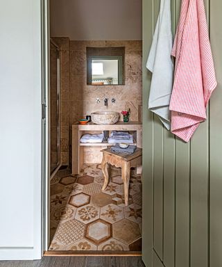 A country cloakroom with a stone basin and cream and brown mosaic floor tiles