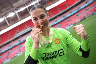 Mary Earps of Manchester United bits her Adobe Women's FA Cup winners medal as she poses for a photograph after the Adobe Women's FA Cup Final match between Manchester United and Tottenham Hotspur at Wembley Stadium on May 12, 2024 in London, England.