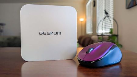 Geekom A6 standing upright on a table next to a computer mouse. 
