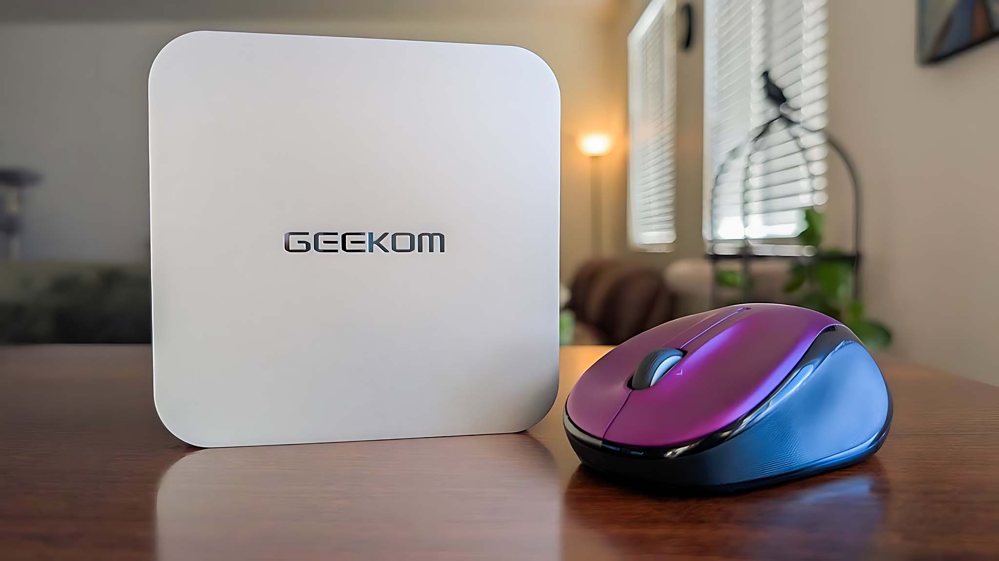 Geekom A6 standing upright on a table next to a computer mouse.