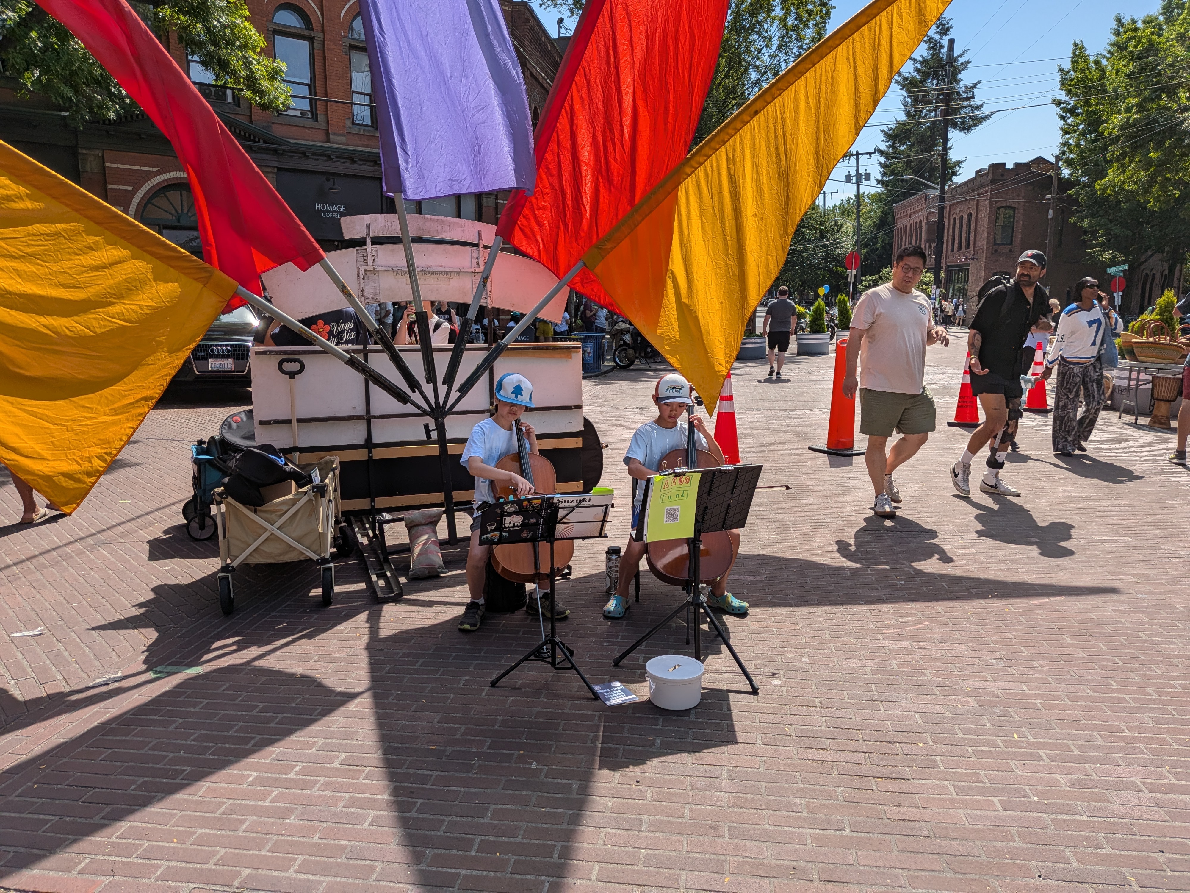 Two kids playing instruments in front of colorful flags