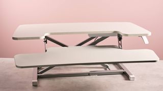 The Flexispot M17 sits on a stone-effect desk in front of a pink background.