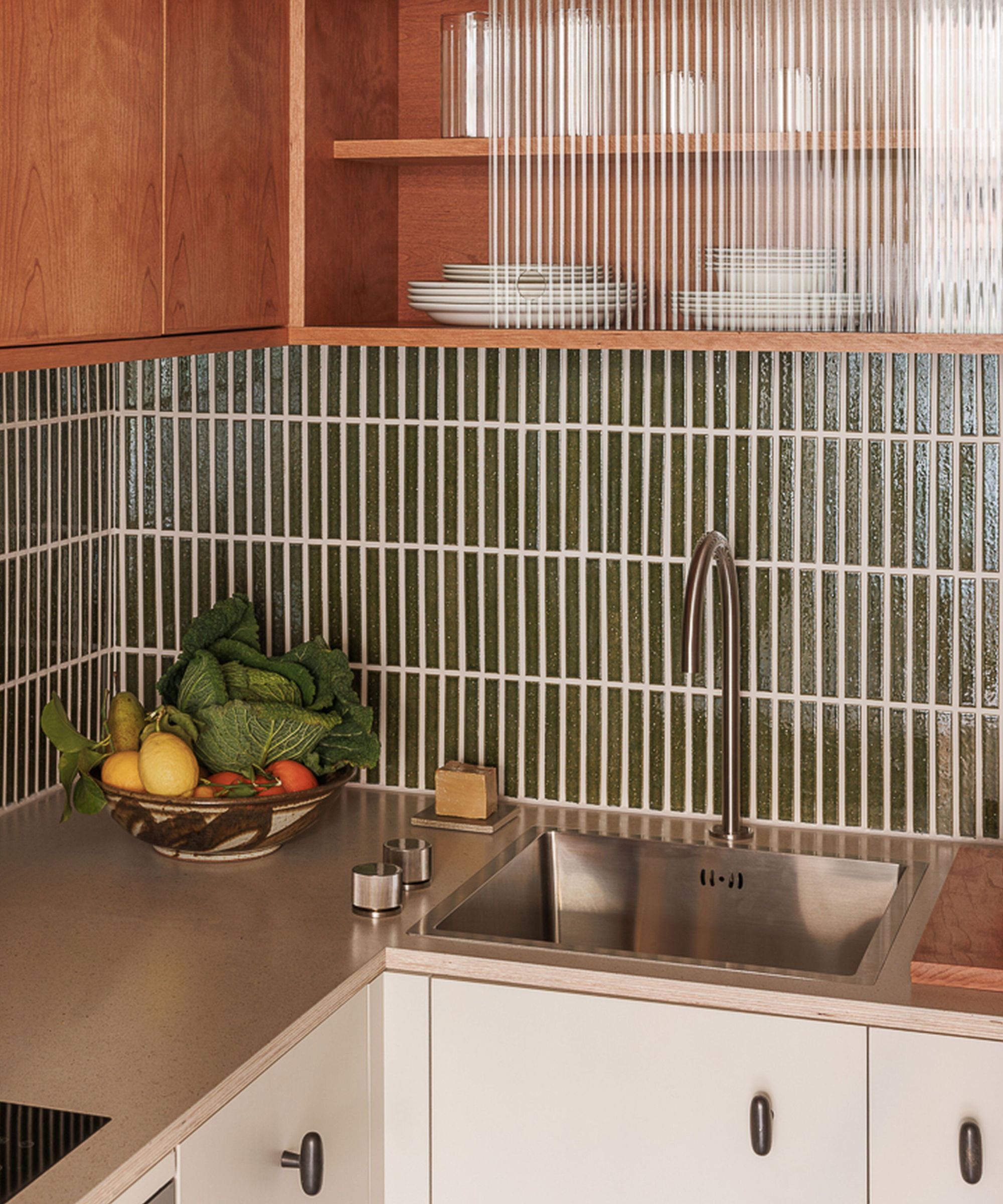 Modern kitchen worktop made from no-chi resin with a slim green tiles splashback