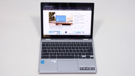 An open and powered on laptop against a white background, facing forward, with images and text displayed on a website on its screen