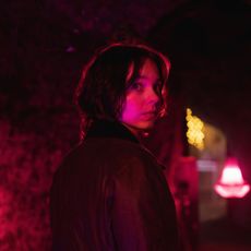 emma myers as pip looking over her shoulder walking down a dark red lit street in a good girl's guide to murder season 2
