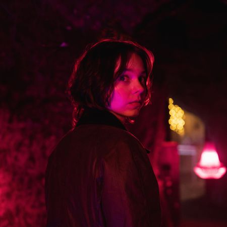 emma myers as pip looking over her shoulder walking down a dark red lit street in a good girl's guide to murder season 2