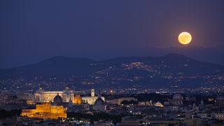 The July full moon rises over Rome, Italy in summer 2022.
