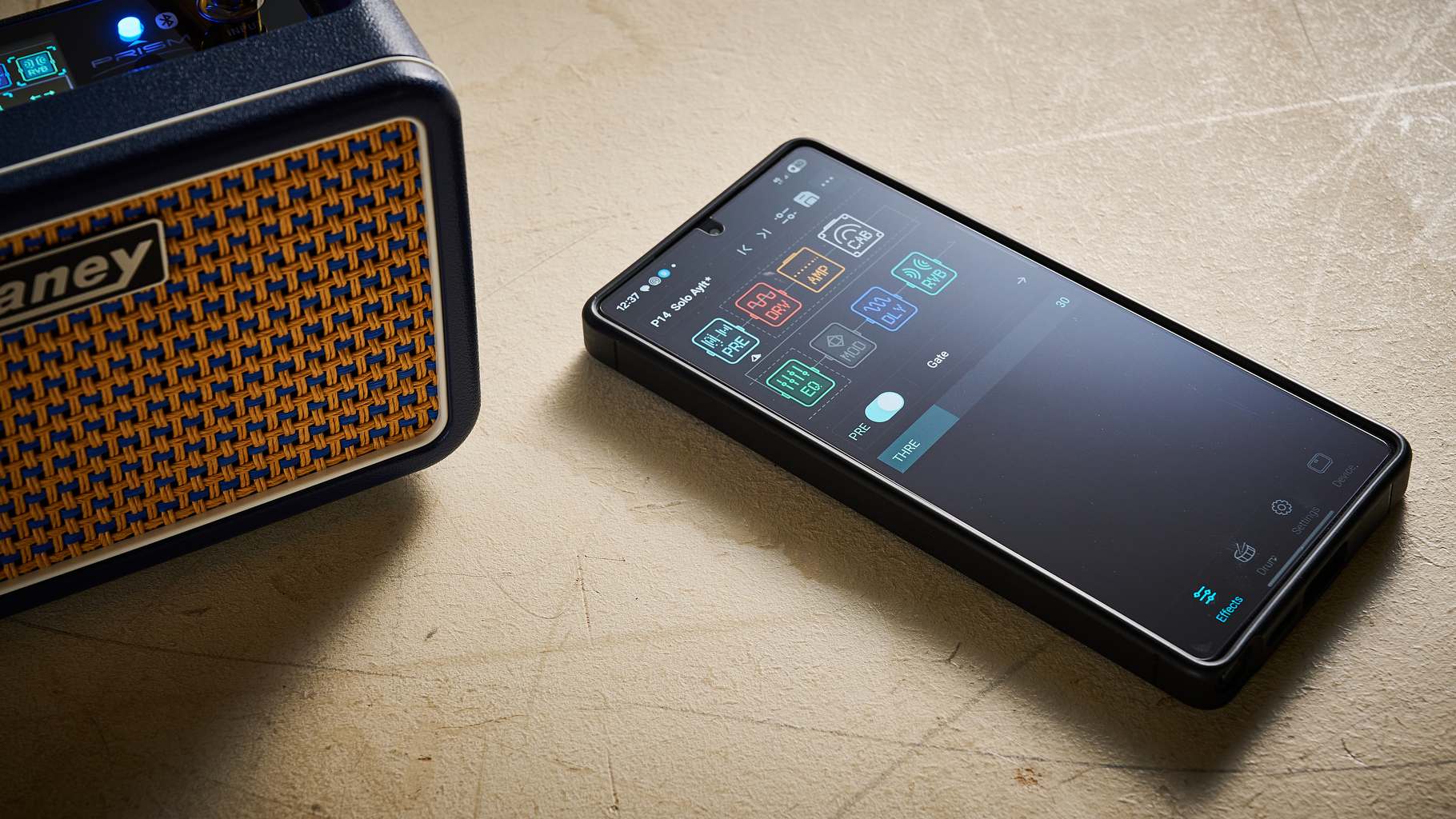 A smartphone lies next to a Laney Prism Mini guitar amp