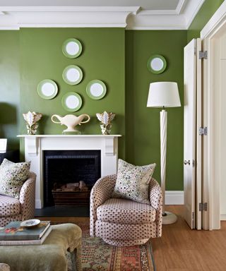 Green walls, hanging plates, white fireplace and lamps