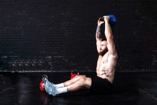 Man performing a sit-up holding a kettlebell above his head