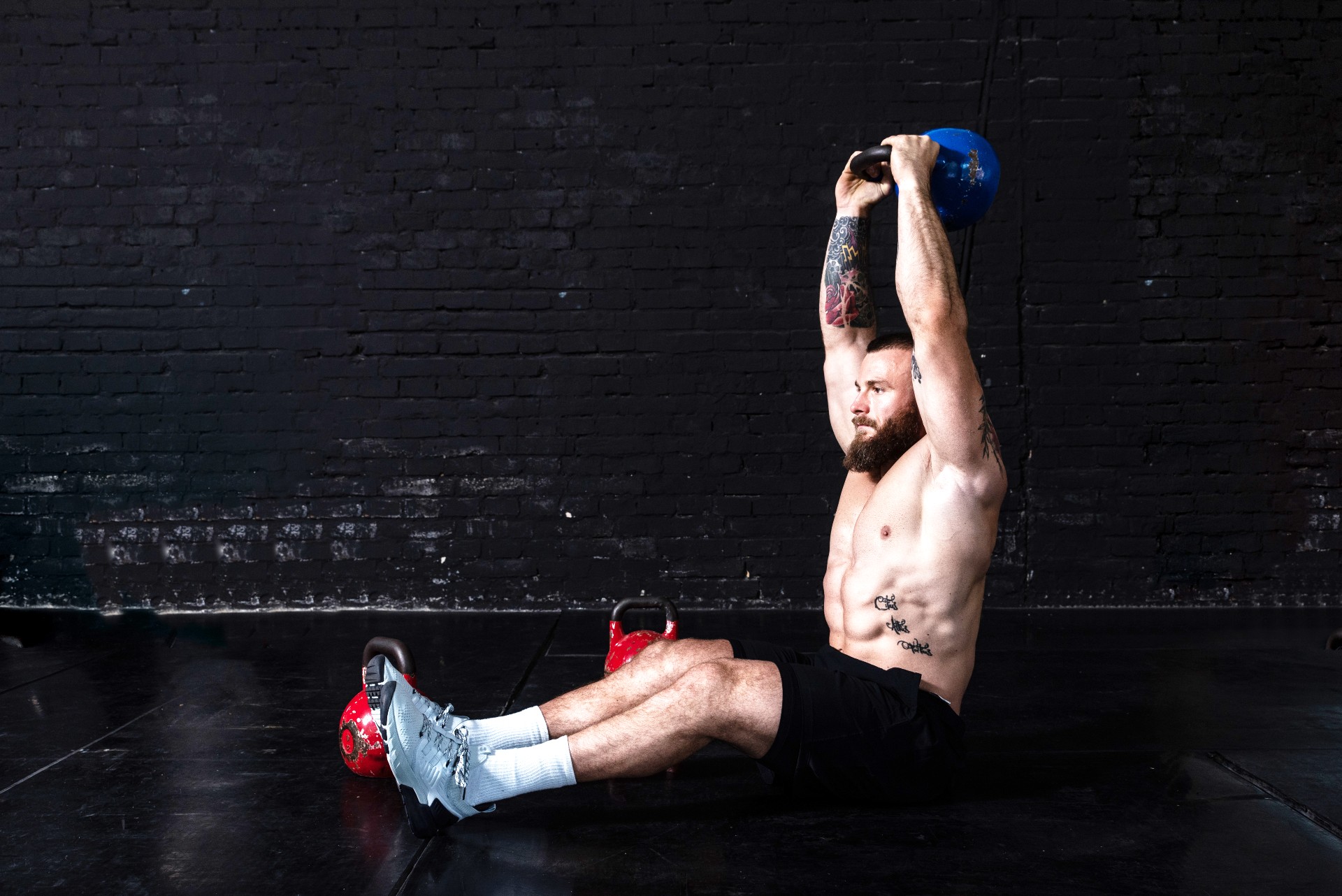 Man doing sit-ups with a kettlebell overhead