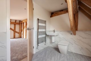 Chrome towel radiator in farmhouse bathroom with wood detail and neutral floor
