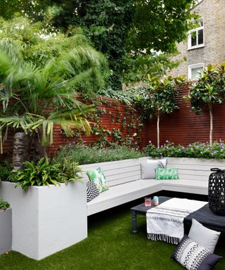 A north-facing garden idea with a white bench, ferns and fronds