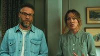 Seth Rogen and Olivia Wilde stand in their living room with a confused look on their faces.