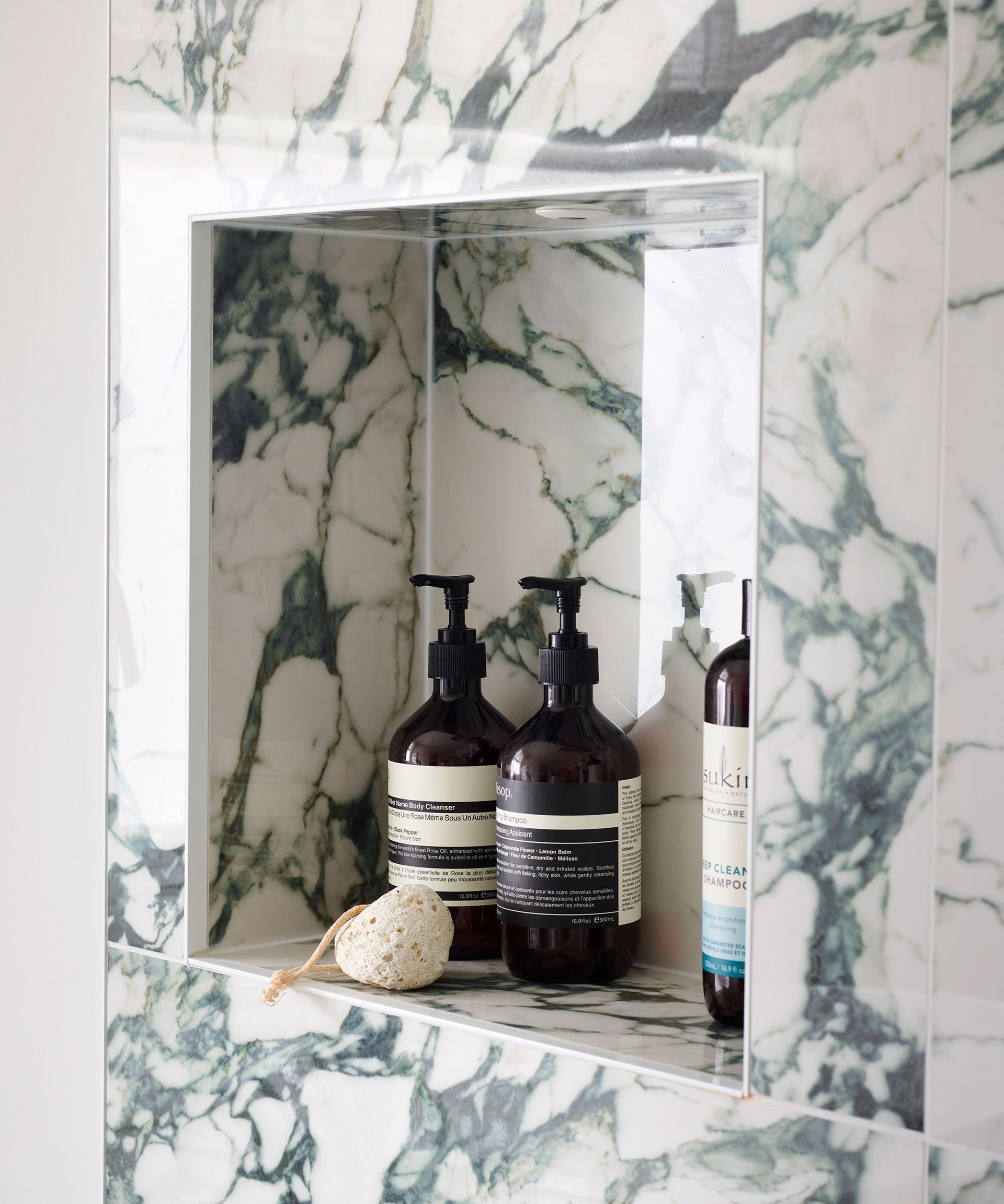 Built-in bathroom cubby in marble shower to house bathroom toiletries