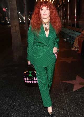 Natasha Lyonee wearing a green suit