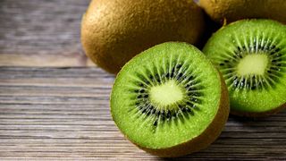 Multiple kiwi fruits on a wooden surface