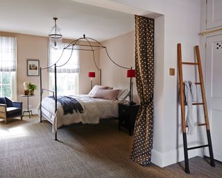 Girls' bedroom ideas with black metal four poster bed and red lamps in a white and pale blush pink scheme.