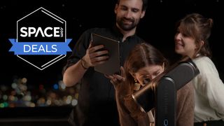 A man and woman looking at a tablet with another woman looking through a Unistellar Odyssey Pro eyepiece with city lights in the background.