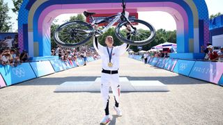 Tom Pidcock holds his Pinarello Dogma XC MTB in the air after winning gold at the 2024 Paris Olympic