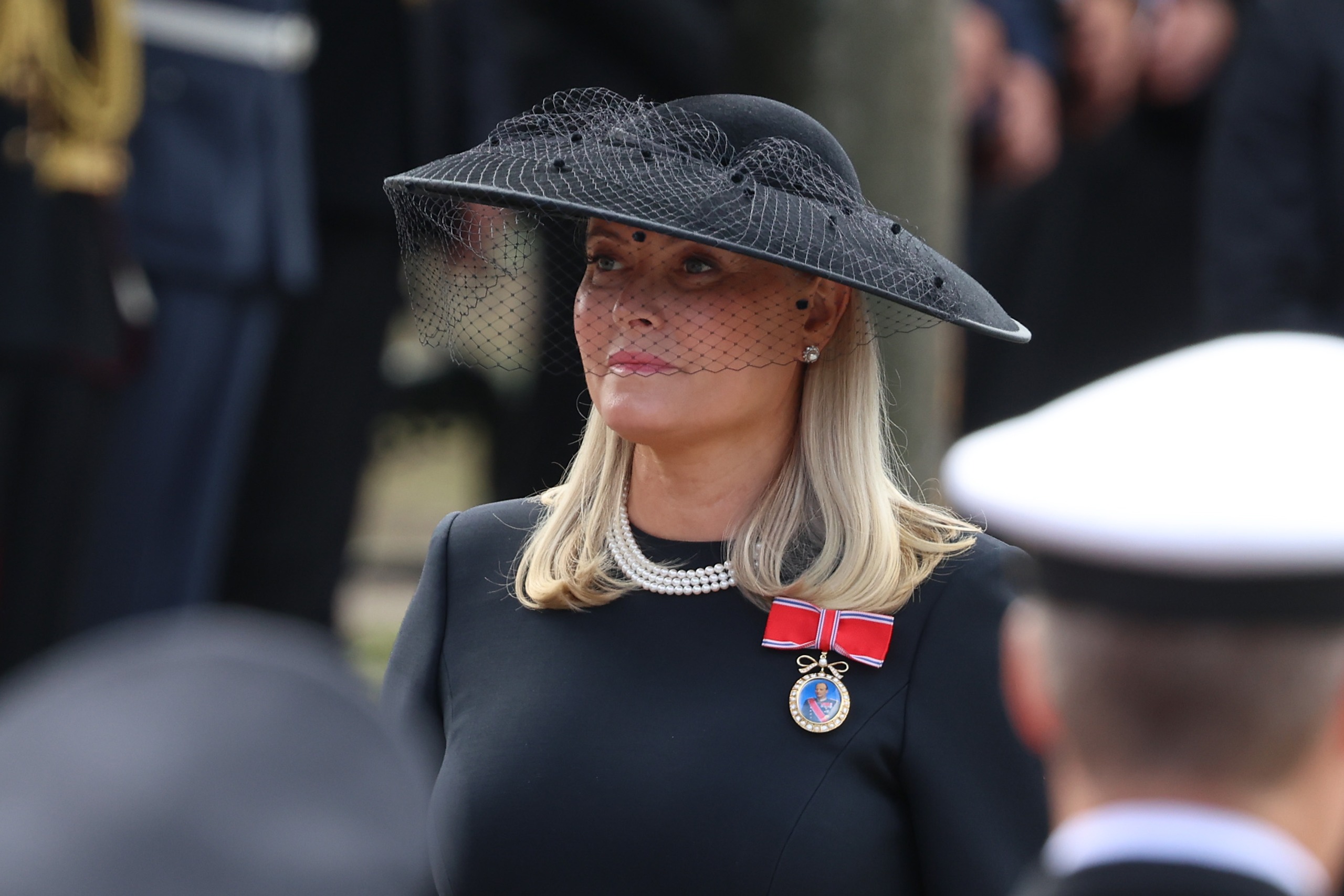 Queen Mette-Marit wearing a black hat and pearls