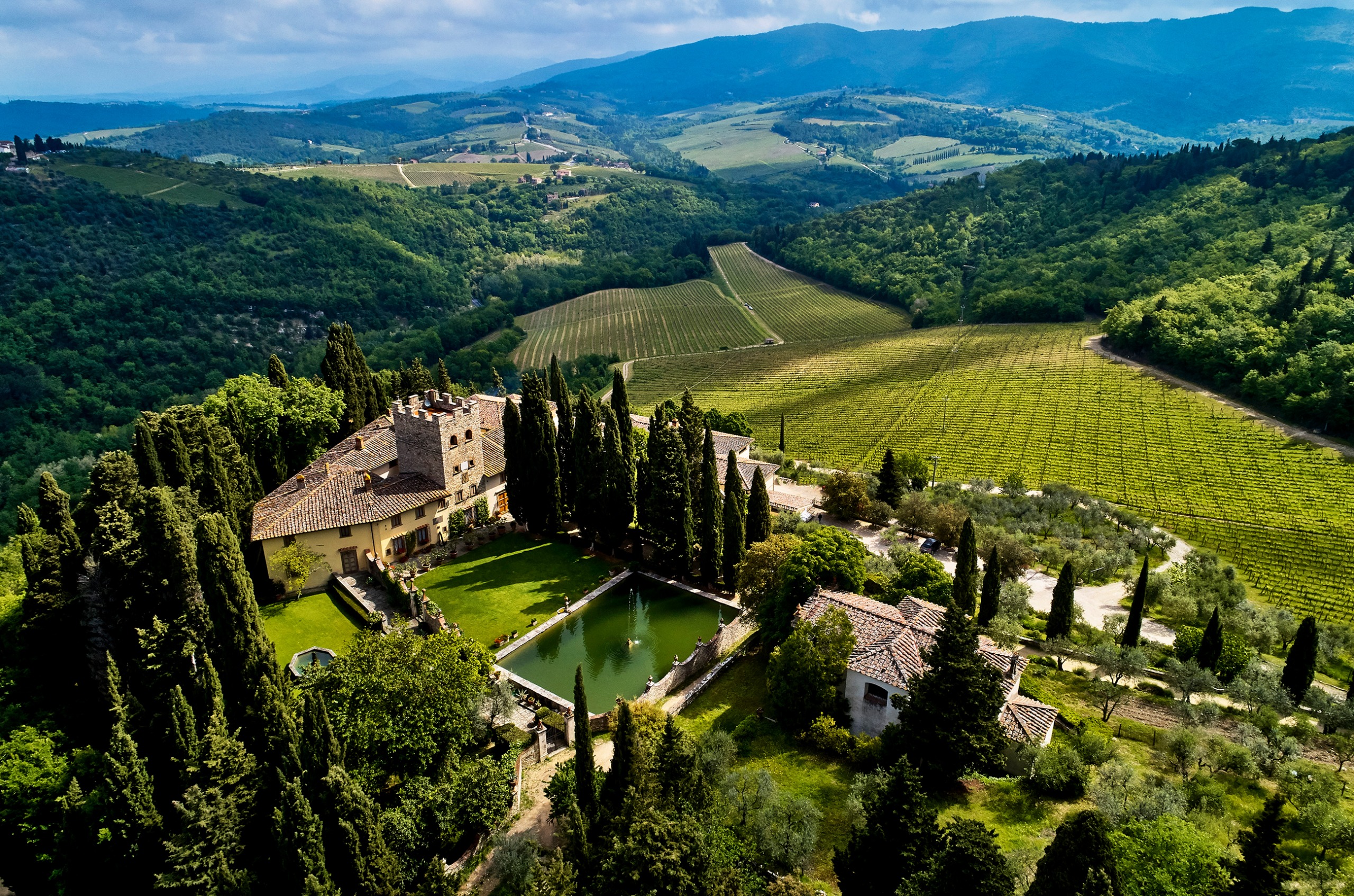 Airel view of Castello di Verazzano winery, surrounded by trees and with a water feature in the middle