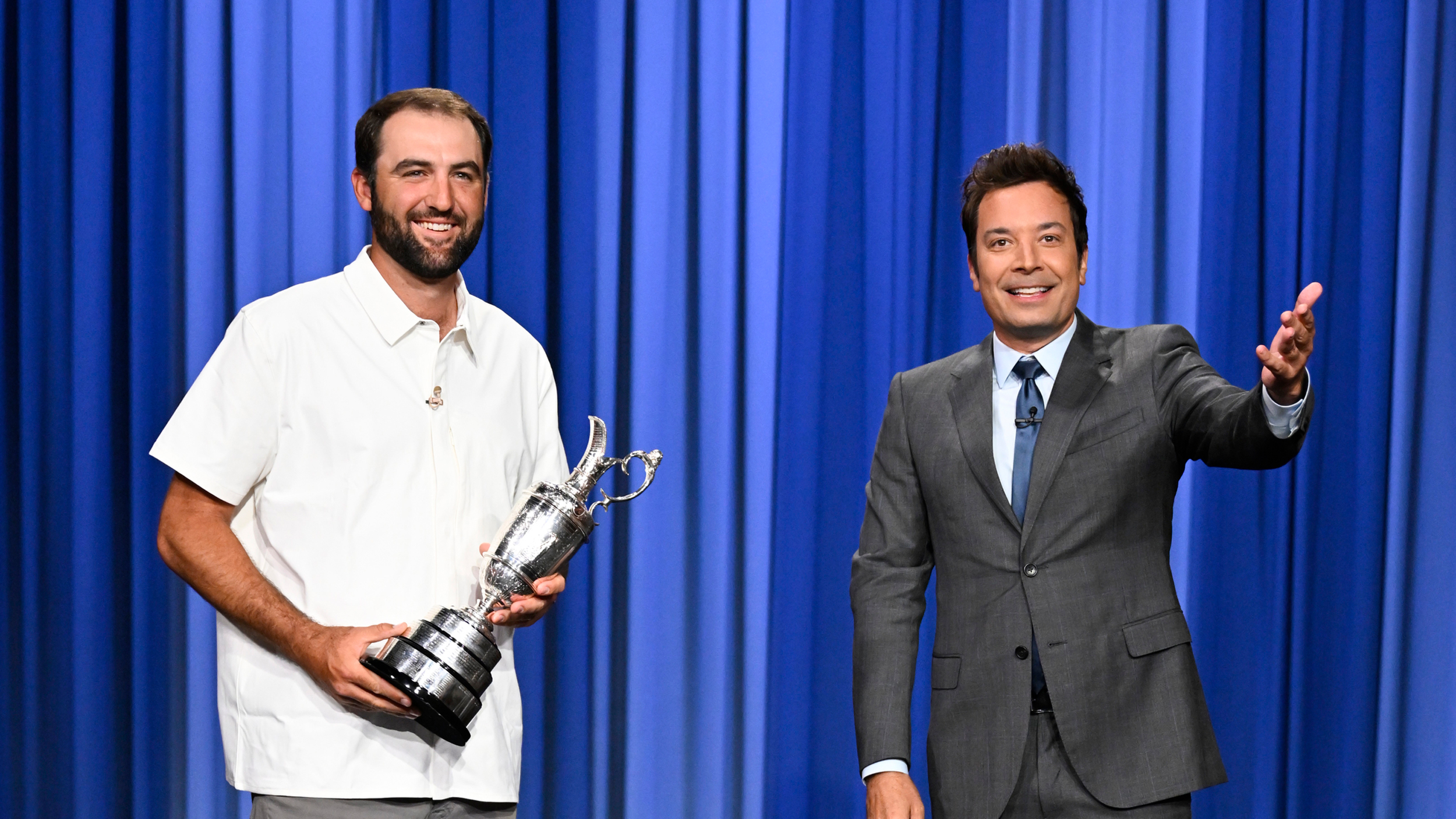 Scottie Scheffler (left) holds the Claret Jug while Jimmy Fallon introduces him to the audience