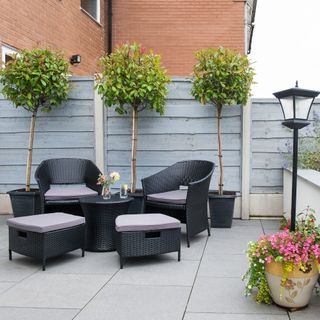 A redesigned low maintenance garden with hard landscape, Grey fencing and seats and a table, and a low wall with concrete patio