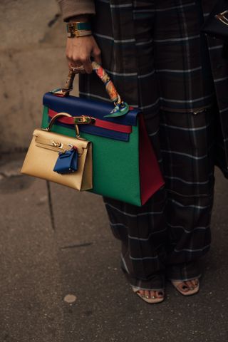 a woman at fashion week carries three hermes bags linked with one another