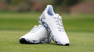 A picture of the G/Fore MG4+ golf shoes resting on the golf course showing off their excellent camo print soles