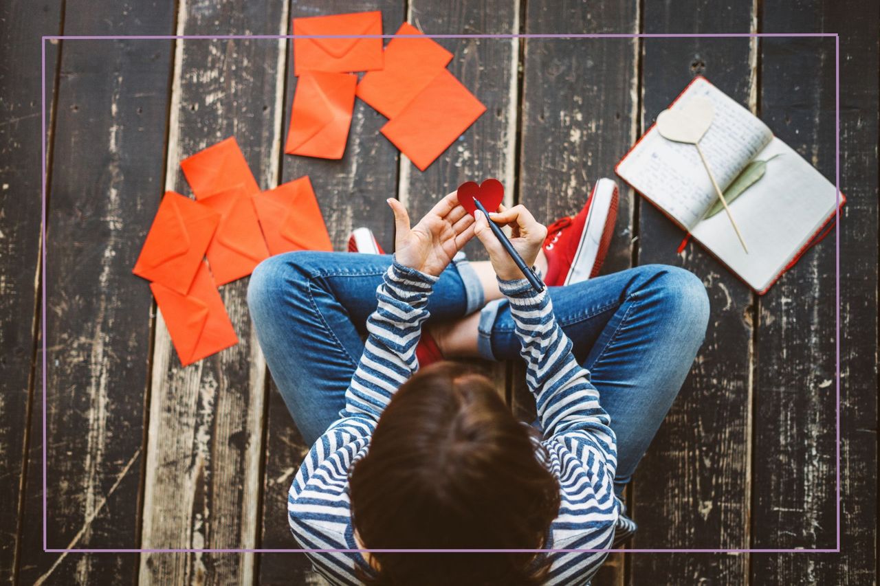 child sat cross legged writing valentine&#039;s cards