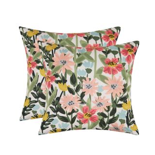 Two colorful outdoor throw pillows with pink, yellow, and red flowers, with one in front of the other