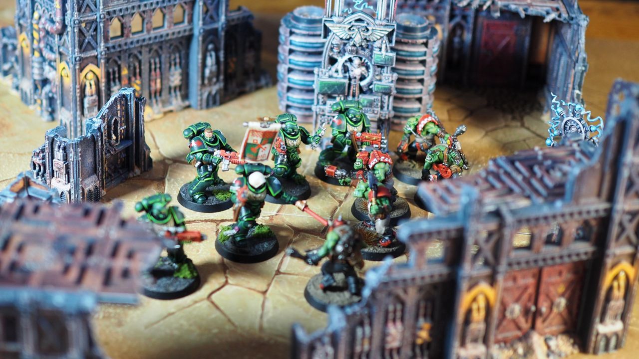 Warhammer 40K Space Marines fight Orks in a pre-painted battlefield