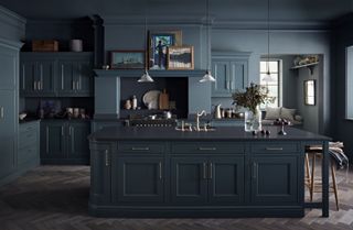 A dark grey and smoky blue kitchen with a black countertop and brass taps