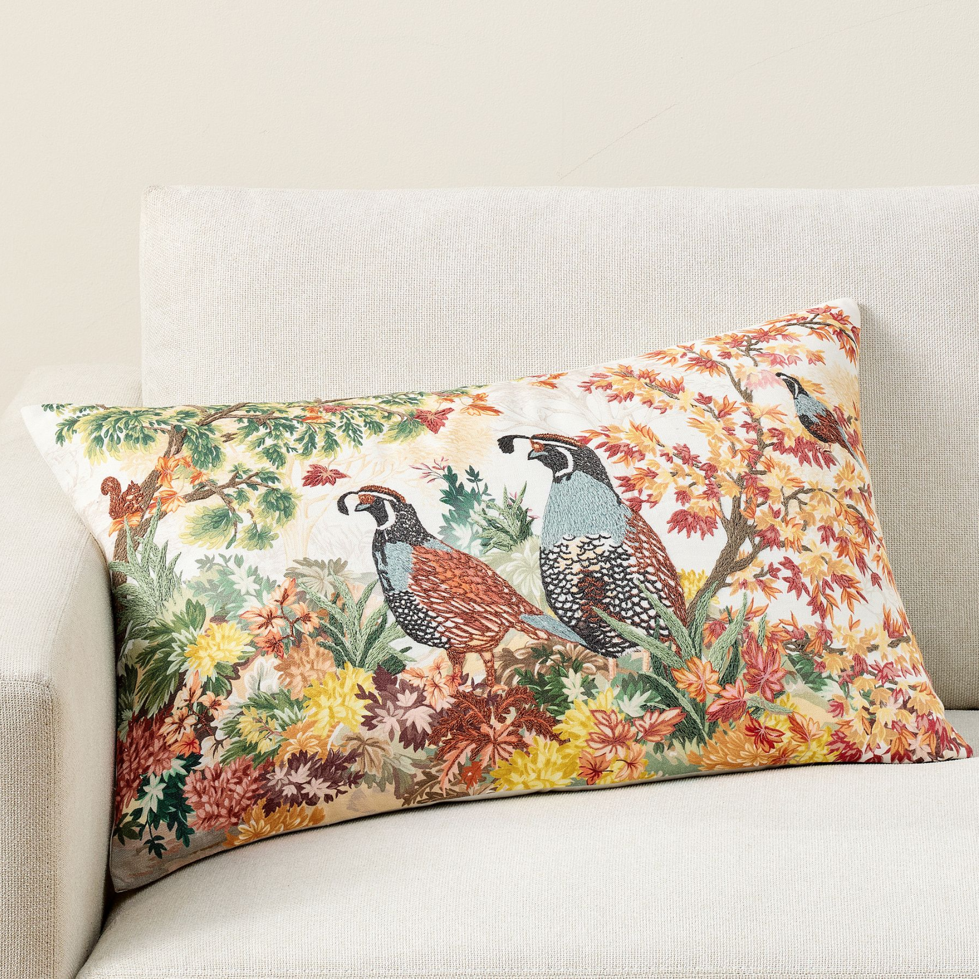 a pillow with two pheasants and floral designs
