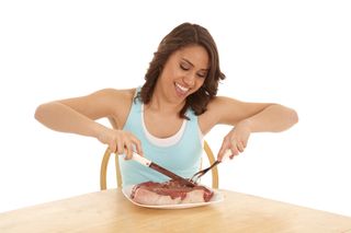 A woman looking super happy to dig into a huge raw steak. 